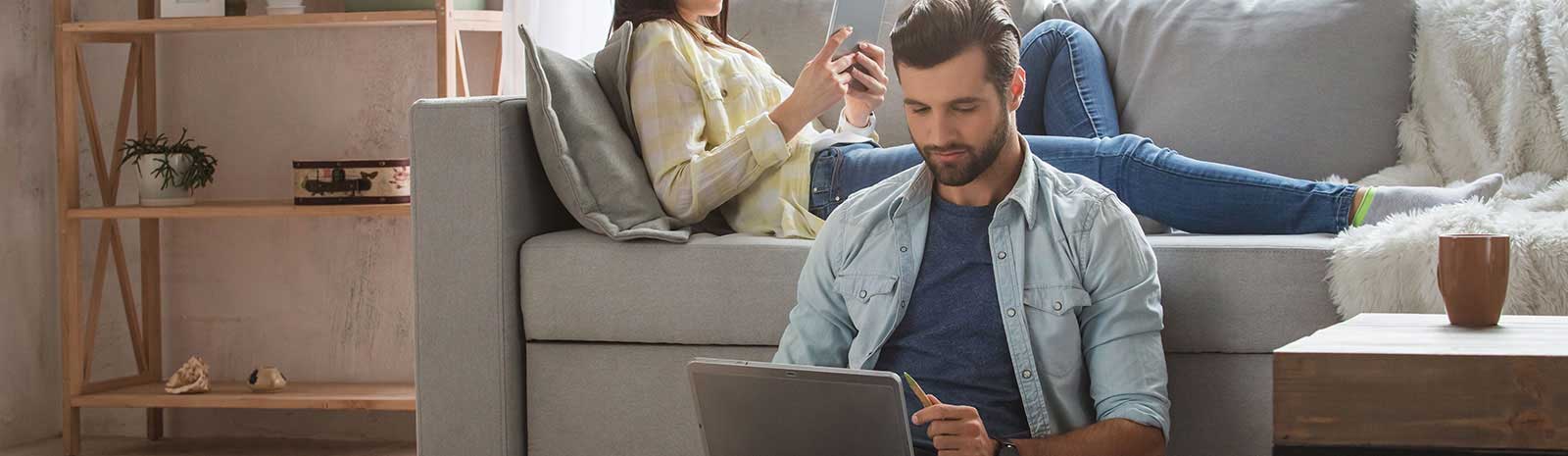 Man and woman relaxing while on a laptop and a mobile phone.