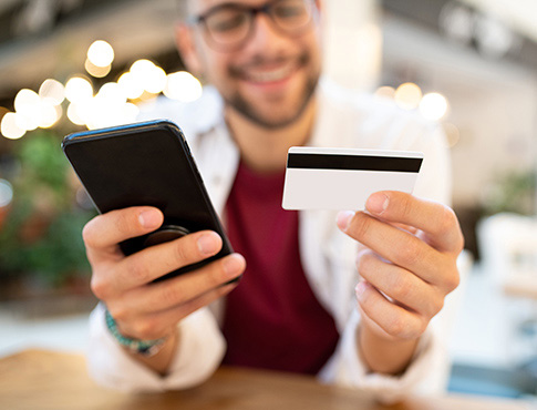 Man holding a debit card and a mobile phone