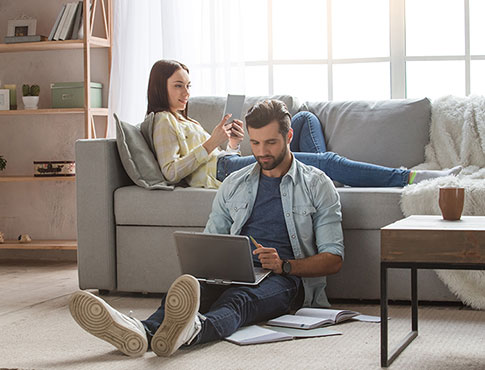 Man and woman in the living room using mobile devices.