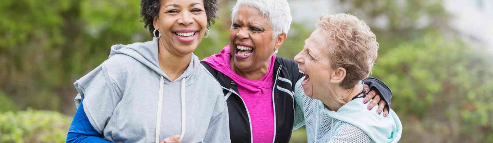 Three mature women laughing in a park.